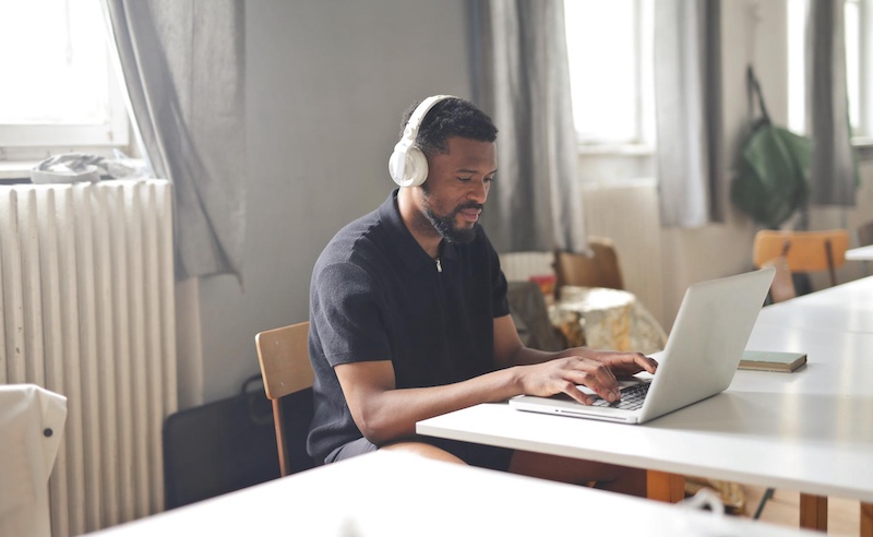 Man with headphones on speaking into laptop